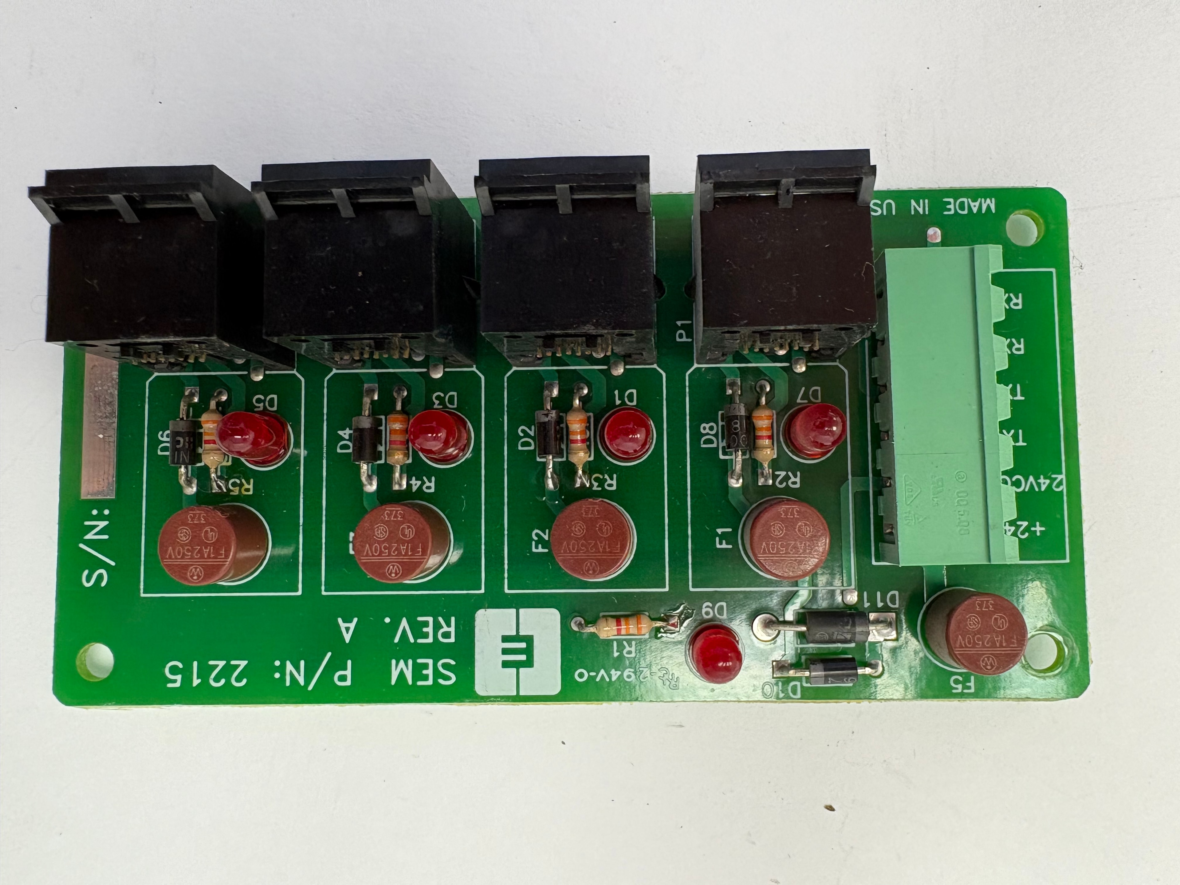 SEM P/N 2215 Rev A green relay output board — four relay sockets, F1A250V fuses, red LED indicators, +24V and 24VCOM terminals, Made in USA